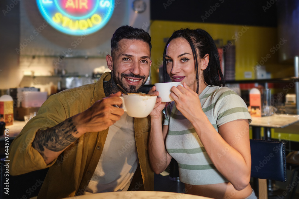 Heterosexual couple looking at camera drinking coffee
