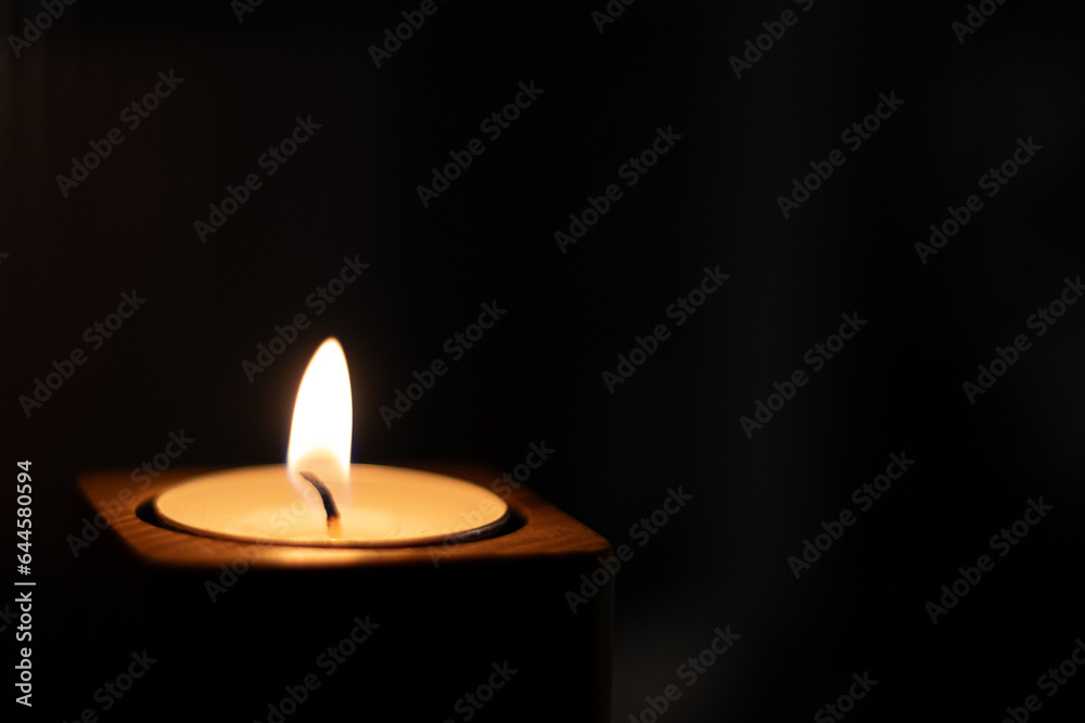 Close-up of flame burning on candle isolated on a black background. - Bottom Left Corner Close-up of flame burning on candle isolated on a black background. - Bottom Left Corner
