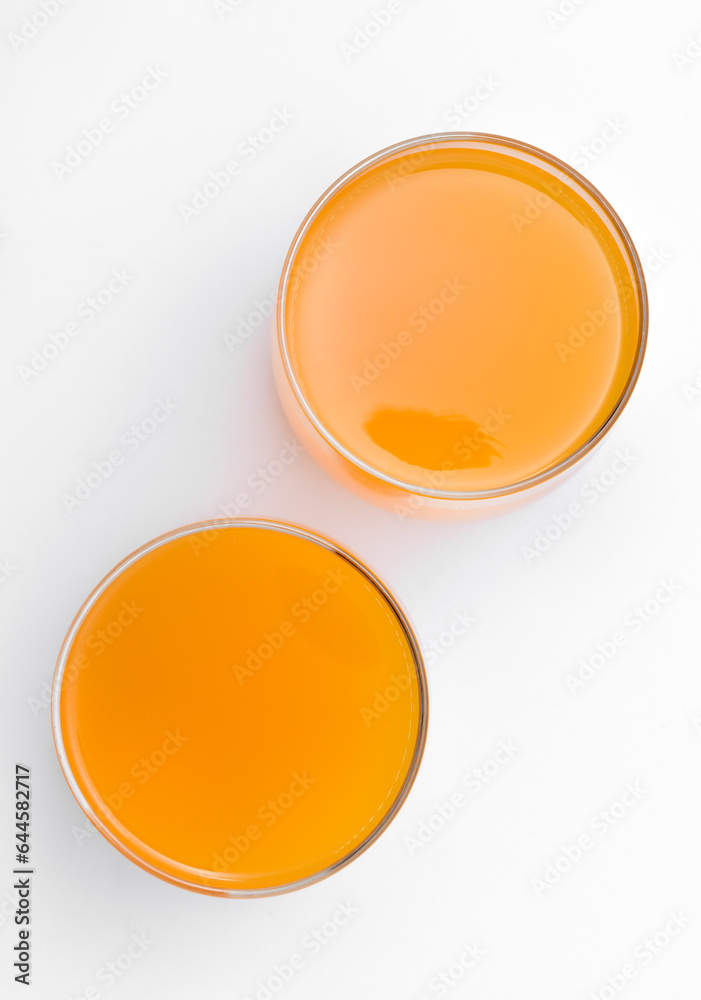 Glass glasses with orange juice on a white background. Delicious orange cooling drink. Glass glasses with orange juice on a white background. Delicious orange cooling drink.