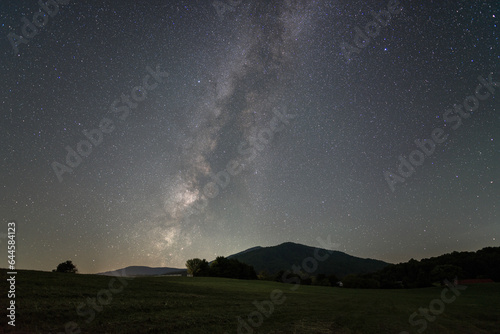 The Milky Way sinks behind Old Rag Mountain of Shenandoah National Park in Virginia, viewed from a mowed farm.
