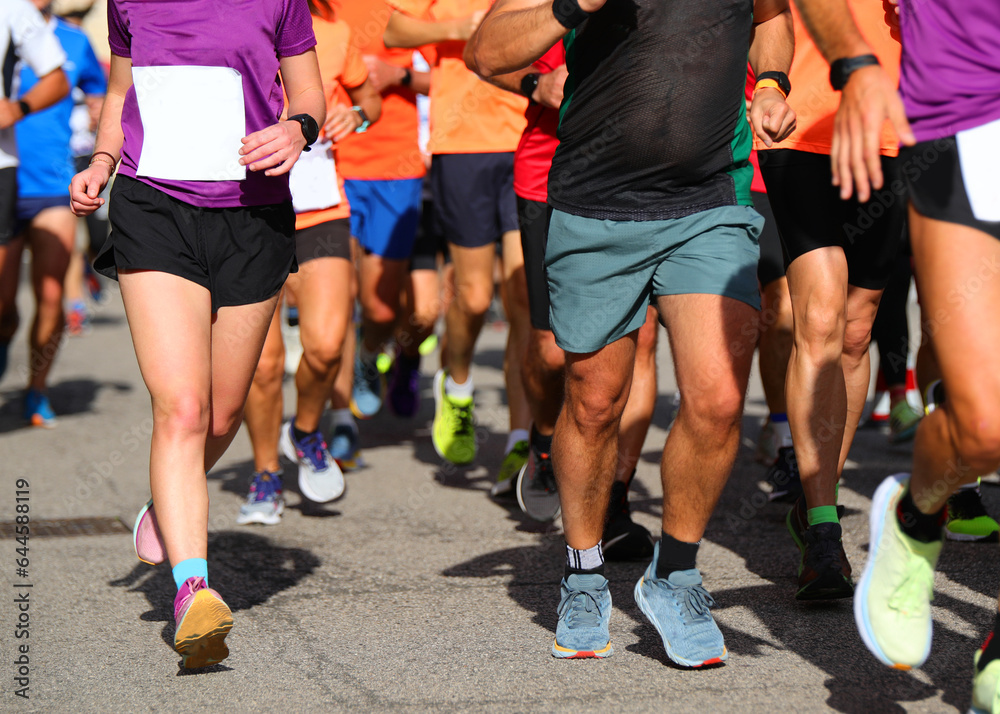 legs of male and female runners with sneakers running during marathon legs of male and female runners with sneakers running during marathon