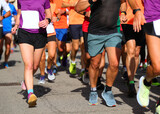 legs of male and female runners with sneakers running during marathon