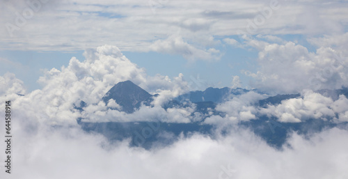 view of clouds and blue sky and mountains in between from a low flying aircraft photo