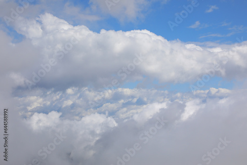 view of the white clouds and blue sky from the window of an aircraft during the journey