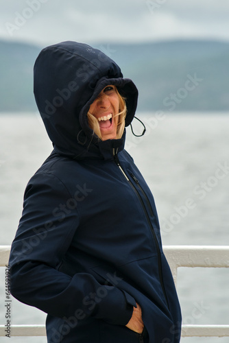 Mujer con capucha viajando en barco por un lago con lluvia