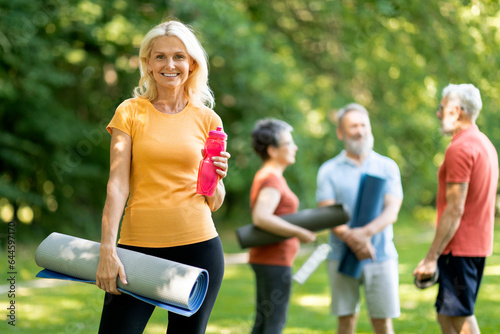 Portrait Of Beautiful Sporty Senior Woman Training Outside With Group Of Friends