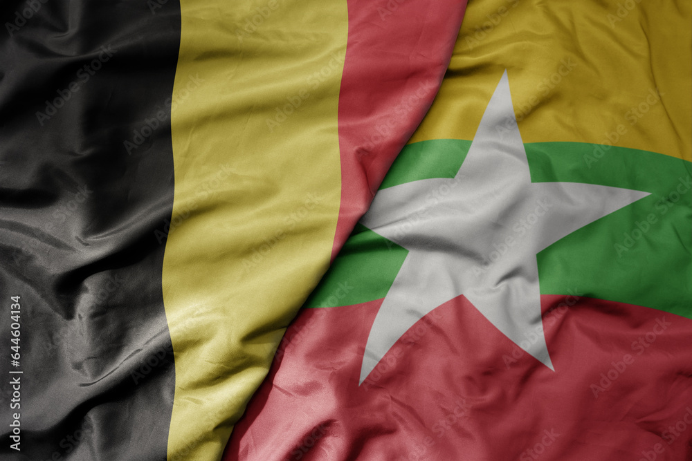 big waving national colorful flag of belgium and national flag of myanmar .