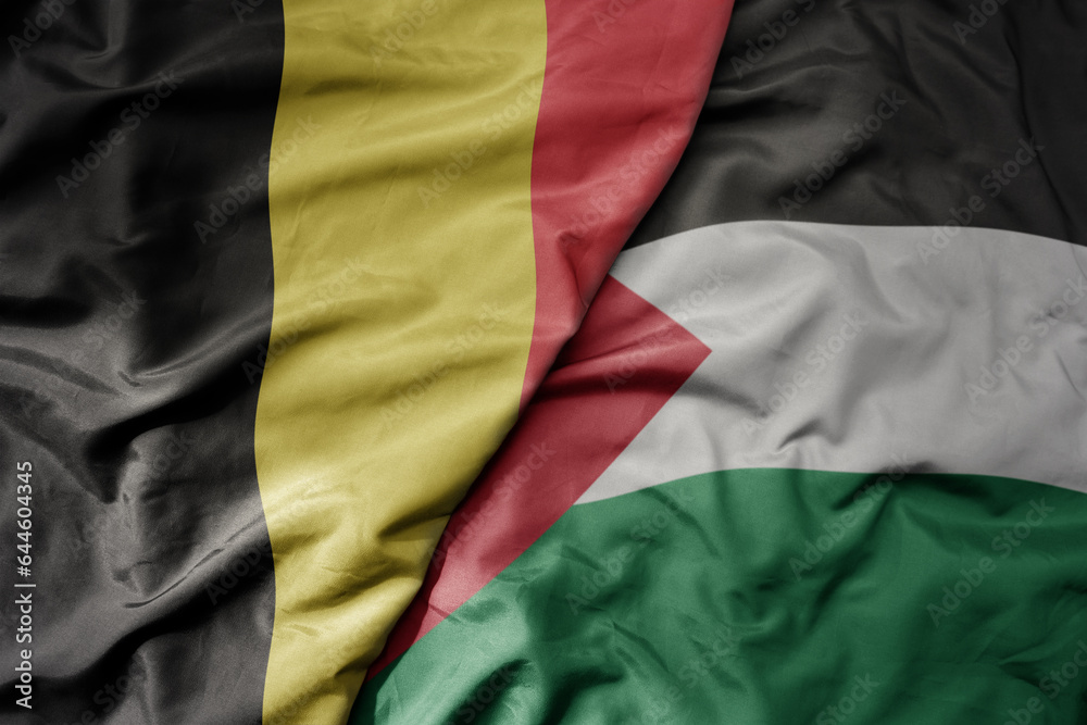 big waving national colorful flag of belgium and national flag of palestine .