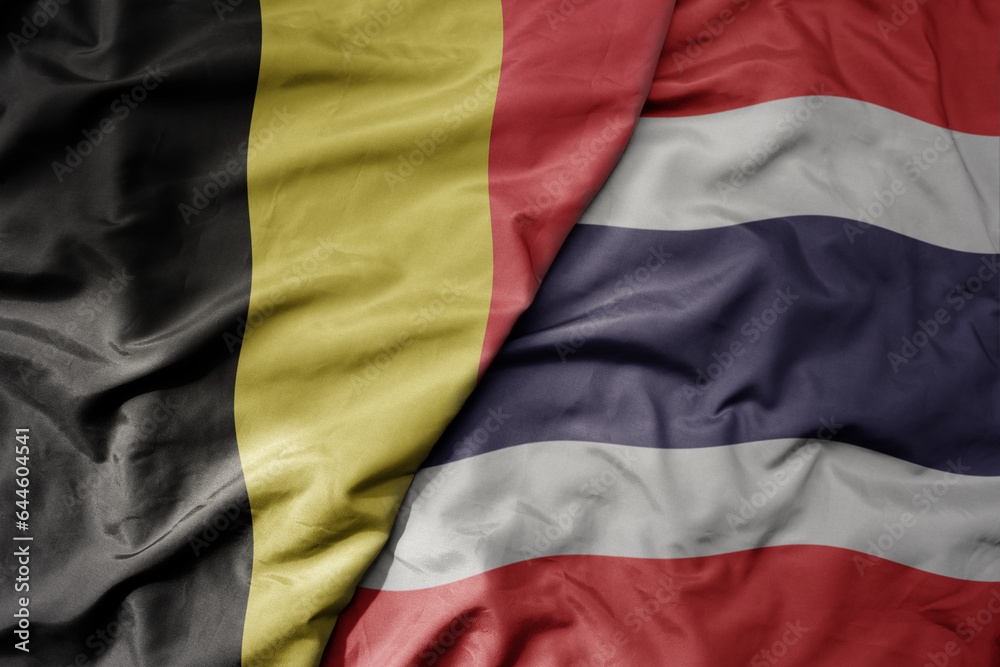 big waving national colorful flag of belgium and national flag of thailand .