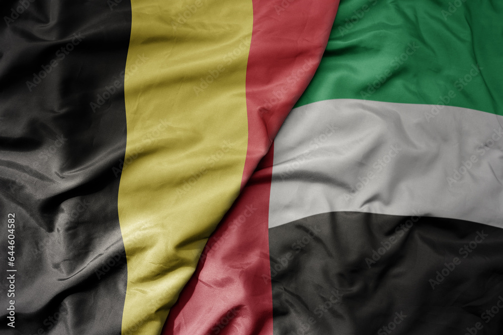 Obraz premium big waving national colorful flag of belgium and national flag of united arab emirates .
