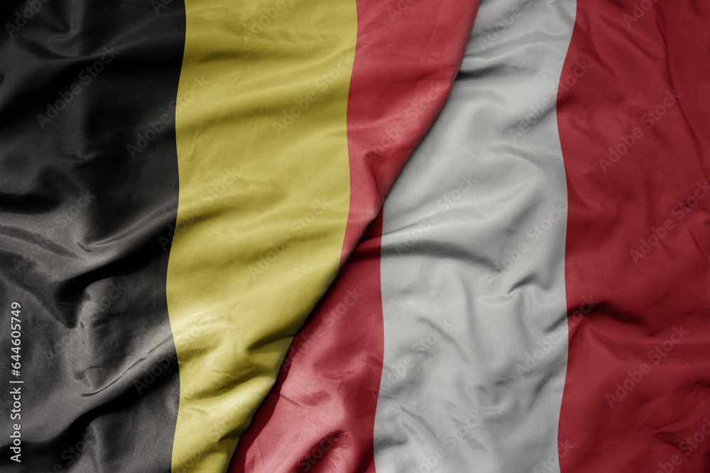 big waving national colorful flag of belgium and national flag of peru .