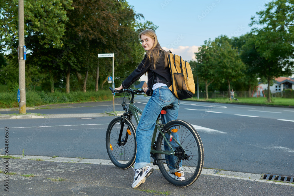 Portrait of teenage student girl with backpack on bicycle