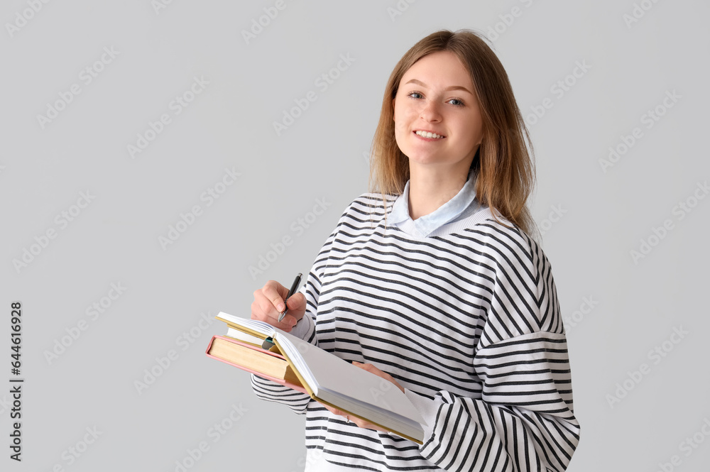 Female student with notebooks on grey background Female student with notebooks on grey background