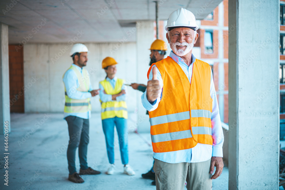 Young attractive architect standing at construction site and showing thumbs up. We're 100% safety compliant. Portrait of a senior man working showing an okay gesture at a construction site