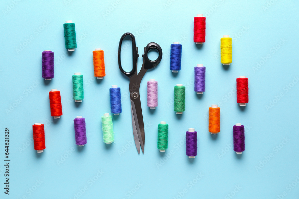 Composition with different thread spools and scissors on color background Composition with different thread spools and scissors on color background