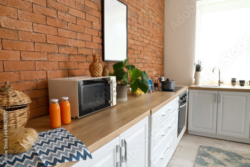 Kitchen counters with microwave oven, utensils and orange juice