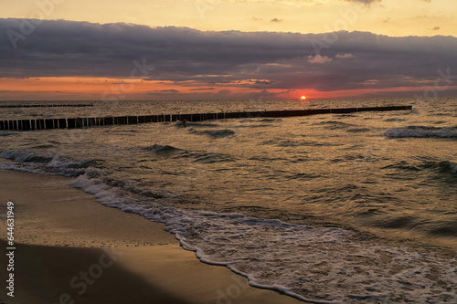 Seascape at sunset in stormy weather. Waves on the sea and dark clouds in the sky. Baltic Sea, Western Pomerania, Poland, Europe.