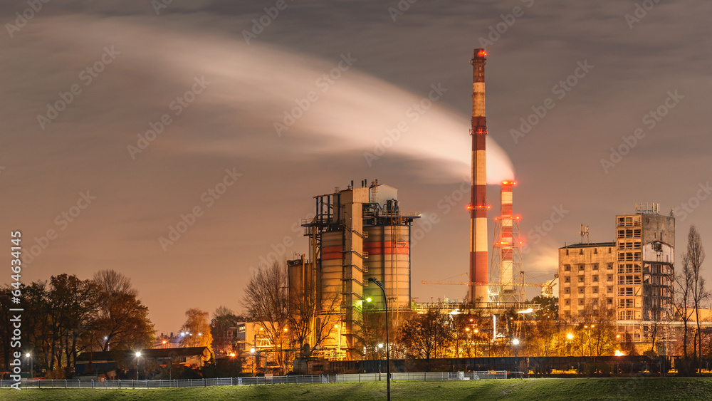 Wroclaw, illuminated municipal  power plant on the Odra River, smoke coming out of a high chimney. View at night.