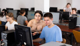 Teenager girl helps friend solve problem on computer in a school class