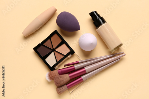 Set of makeup brushes, sponges and cosmetics on color background