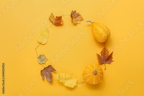 Frame made of pumpkins and leaves on orange background