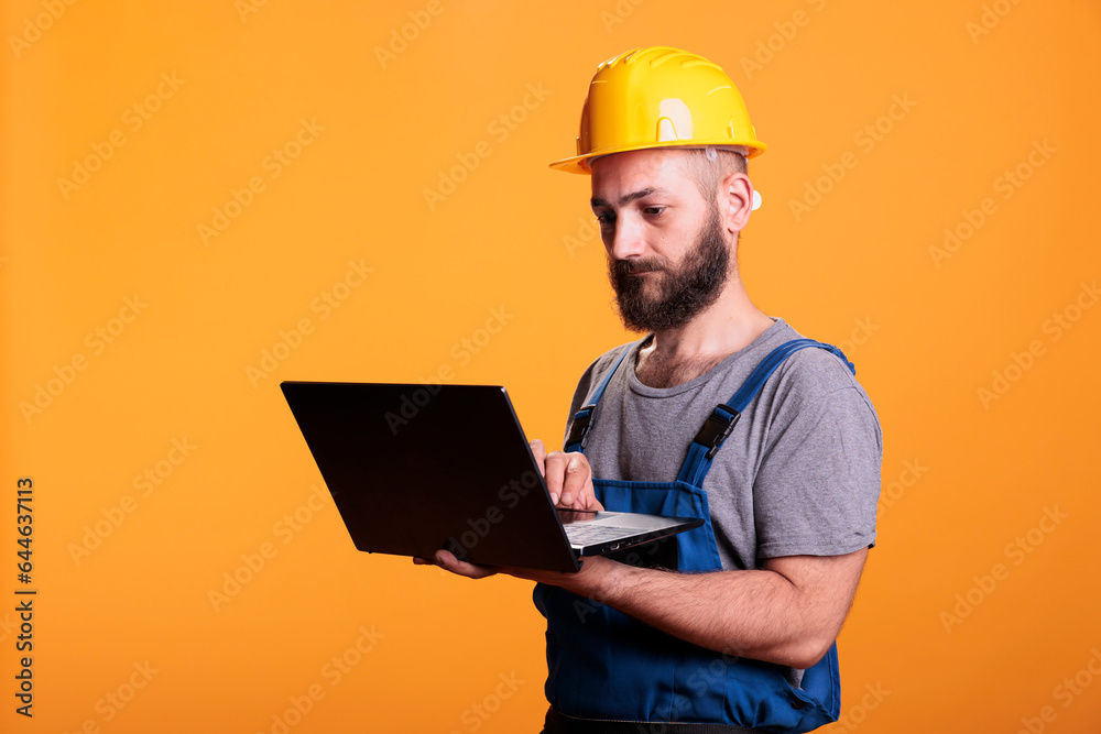 Handyman using laptop to browse internet website, looking for renovating inspiration. Construction site expert holding portable pc with wireless network, constructor at engineering job. Handyman using laptop to browse internet website, looking for renovating inspiration. Construction site expert holding portable pc with wireless network, constructor at engineering job.