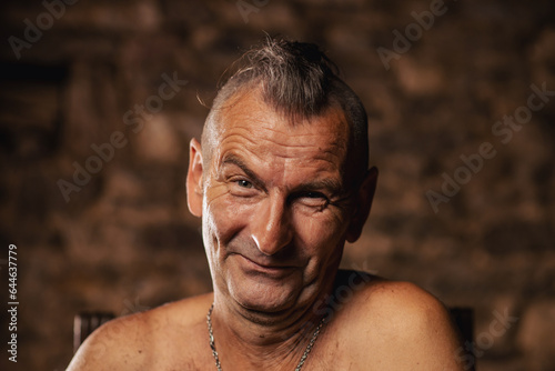 A satisfied older man, sixty years old, smiles and looks at the camera.