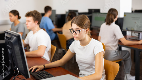 Young girl student with glasses studying on computer in college library, concept of education