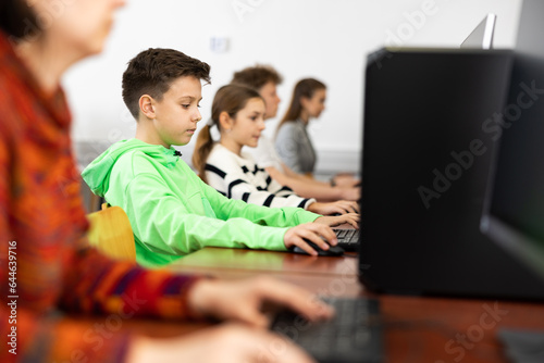 Young caucasian boy learning to use personal computer during lesson in school. © JackF