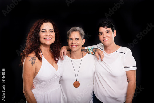 Studio photo of three women, lesbians, happy and free looking at the camera. photo