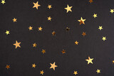 Festive golden stars on black decorating paper background. Backdrop for postcards or banners. New year 2024 decoration packaging. Merry xmas, birthday, happy mothers, fathers, teachers day concept