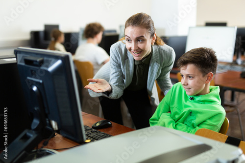 Teacher together with students conduct a lesson on computer education