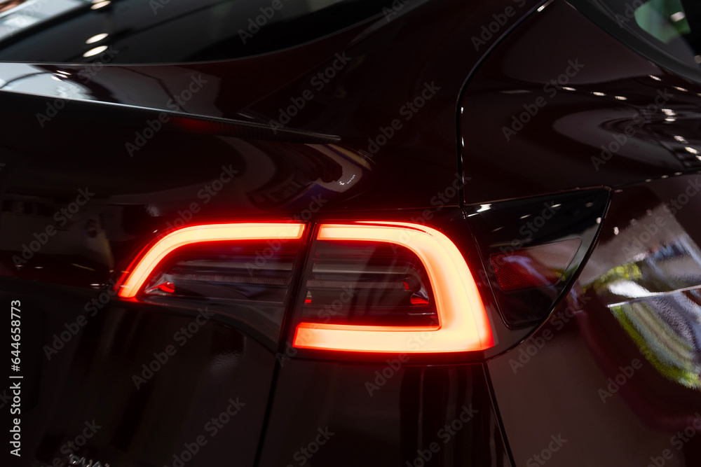tail lights of car in cherry red color in Studio, electric vehicle in showroom, alternative energy development concept, Germany