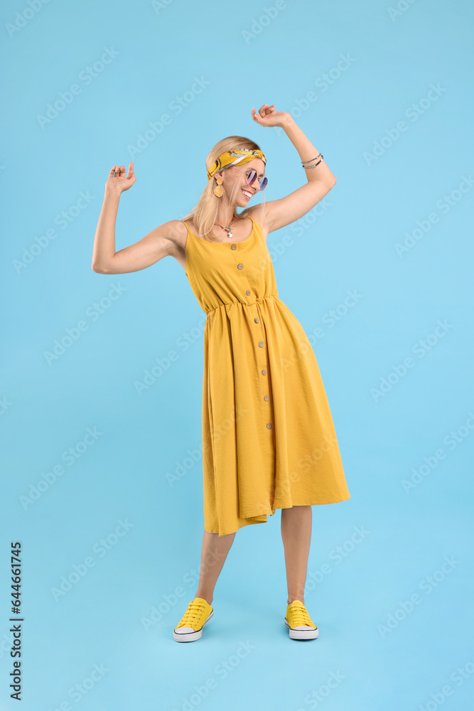 Portrait of smiling hippie woman dancing on light blue background Portrait of smiling hippie woman dancing on light blue background