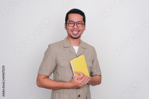 Indonesia young teacher smiling happy while holding a book photo