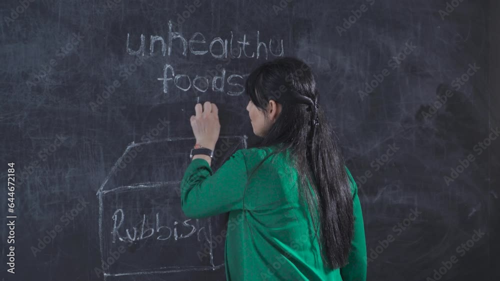 Woman drawing car on blackboard looks happily at camera. Woman drawing car on blackboard looks happily at camera.