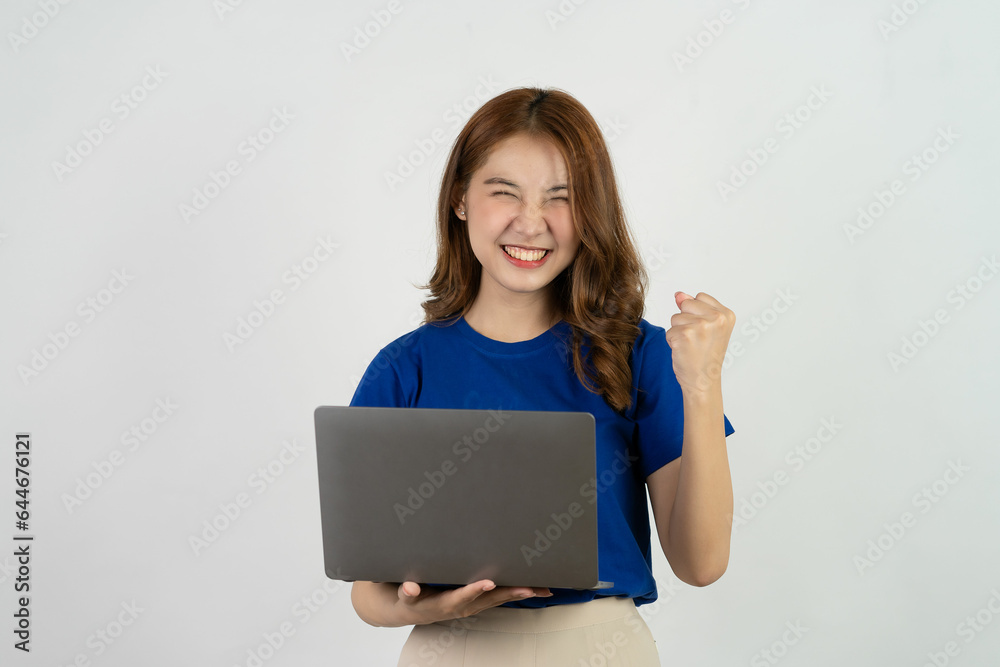 Happy asian woman in blue t-shirt holding laptop while celebrating online marketing success isolated on white background, online shopping concept Happy asian woman in blue t-shirt holding laptop while celebrating online marketing success isolated on white background, online shopping concept