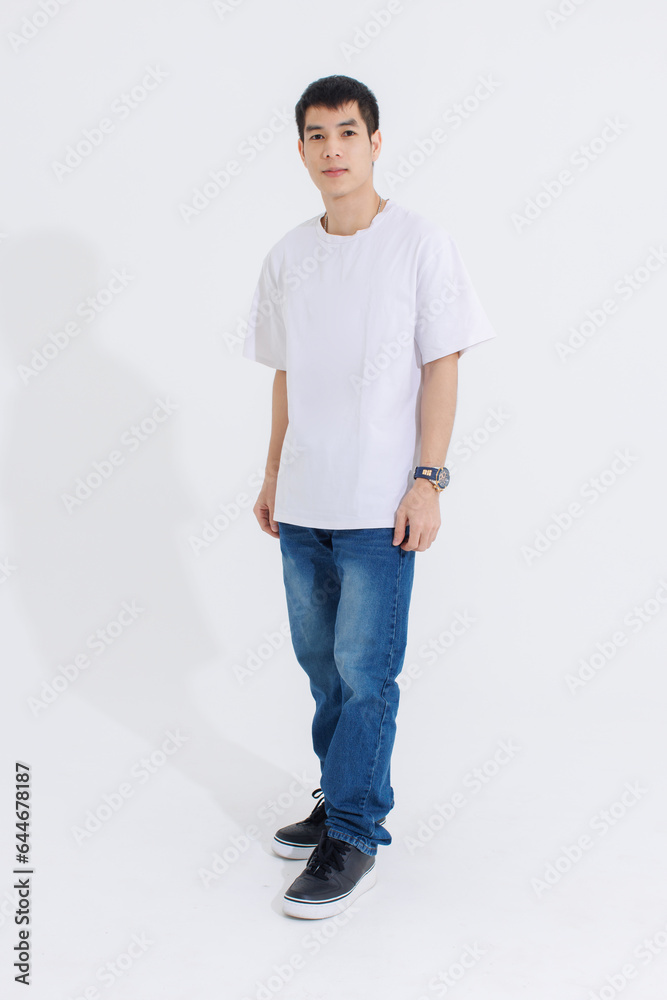 Portrait isolated cutout studio full body shot Asian handsome cool male fashion model in casual fashionable t shirt and blue jeans standing holding hands in pockets look at camera on white background Portrait isolated cutout studio full body shot Asian handsome cool male fashion model in casual fashionable t shirt and blue jeans standing holding hands in pockets look at camera on white background