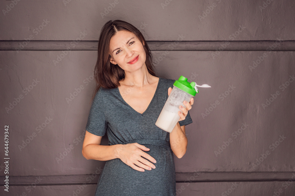 Energetic and fit pregnant woman after 40 enjoying a protein shake for a nourishing boost during her pregnancy journey. Embracing health and wellness for a thriving baby and mom