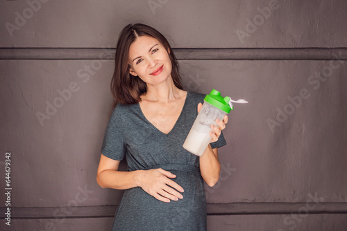 Obraz na płótnie Energetic and fit pregnant woman after 40 enjoying a protein shake for a nourishing boost during her pregnancy journey. Embracing health and wellness for a thriving baby and mom w salonie