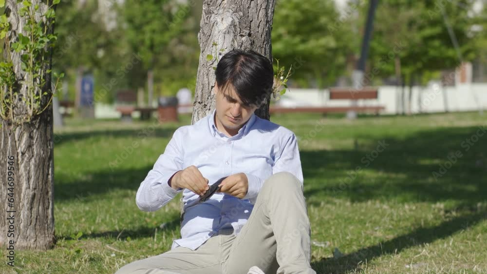 Penniless young man sits outdoors unhappy. Penniless young man sits outdoors unhappy.