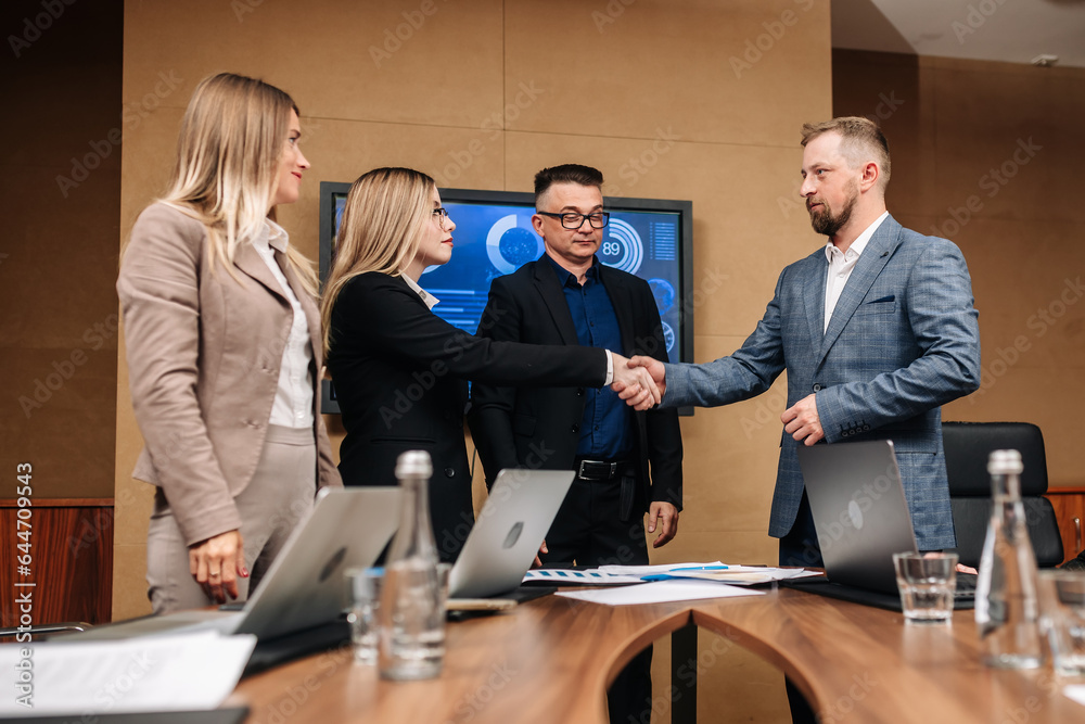 In the meeting room, a team of general directors are talking, finalizing development, shaking hands. Stylish people in a modern conference room. In the meeting room, a team of general directors are talking, finalizing development, shaking hands. Stylish people in a modern conference room.