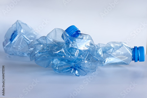 Two crushed blue plastic bottles, recyclable plastic bottle, reduce size, recycling.