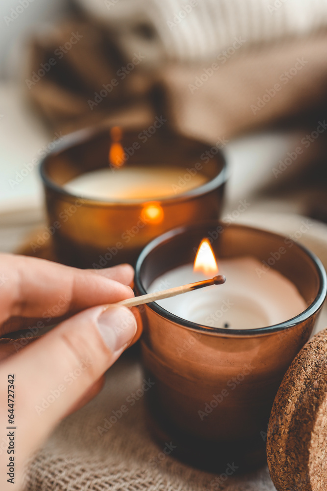 Match in hand lights a candle, cosiness concept Match in hand lights a candle, cosiness concept