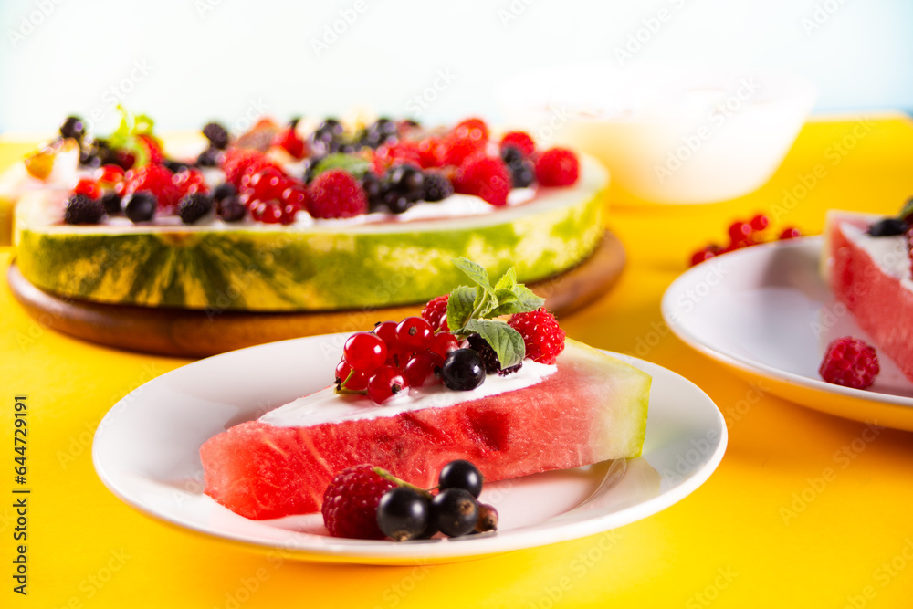 Colorful summer watermelon piece of cake with whipped cream and berries. Refreshment summer dessert food.