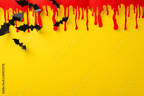 Imaginative Halloween idea. Top view of thematic decorations  eerie blood smears and bats on yellow backdrop  blank space for text