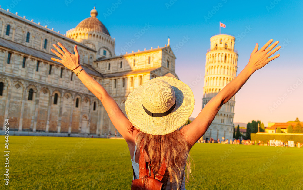 Happy young female traveler in front of the famous leaning tower in Pisa at the sunset- tour tourism, travel, vacation in Italy - Europe