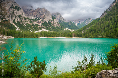 Fototapeta Naklejka Na Ścianę i Meble -  Braies lake surrounded by pine forests and the rocky ranges of the Dolomites in cloudy day, Italy.