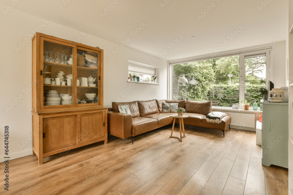 a living room with wood flooring and large windows looking out onto the garden outside from the open kitchen area a living room with wood flooring and large windows looking out onto the garden outside from the open kitchen area