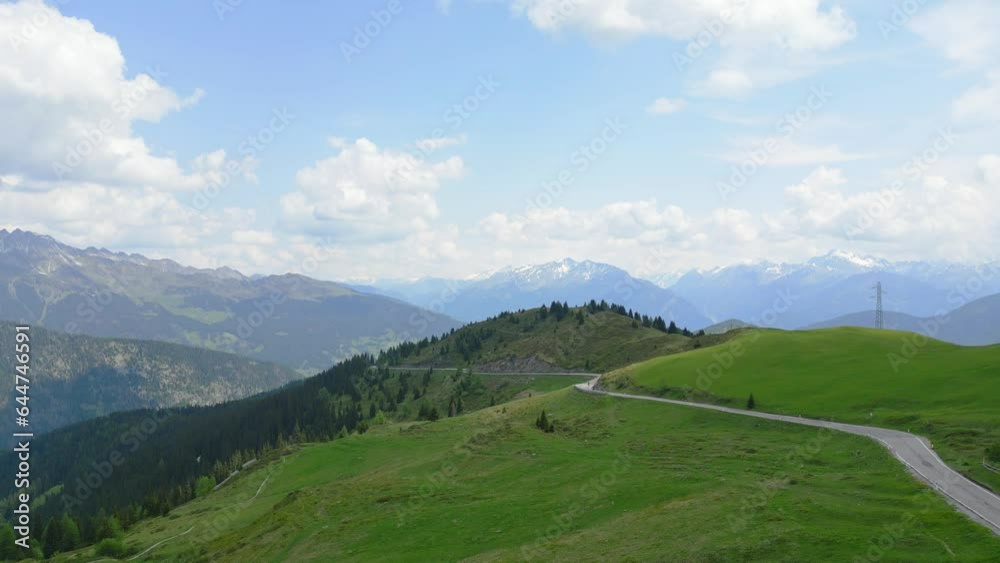 Epic cinematic drone shot of a mountain road with the alps in the background Epic cinematic drone shot of a mountain road with the alps in the background